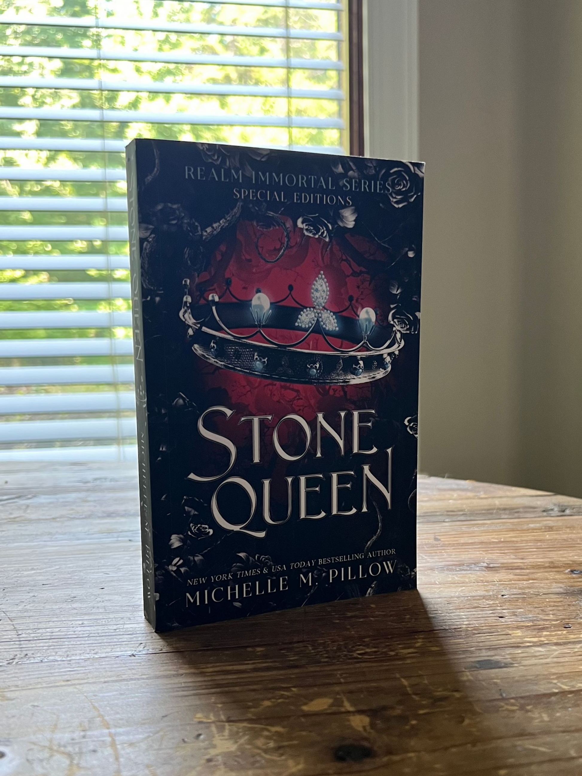 Stone Queen paperback book 3 upright on table.